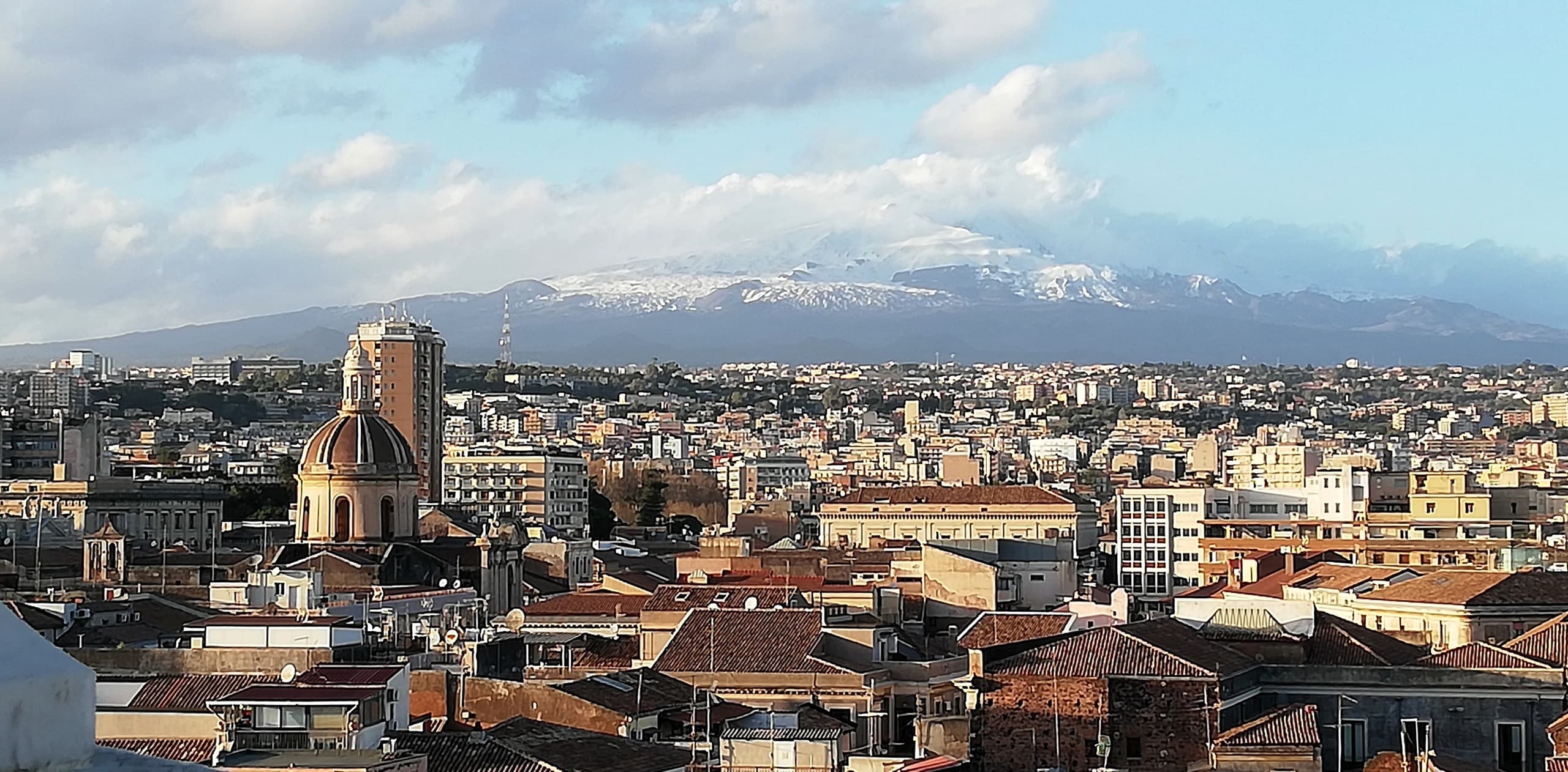 Tetti del centro storico di Catania con l'Etna innevato sullo sfondo